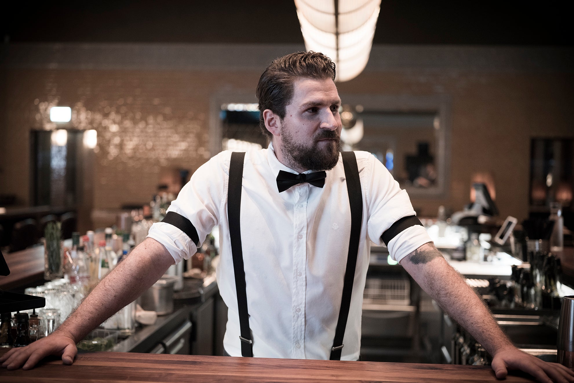 Buddy steht cool an der Bar und sieht zur Seite.